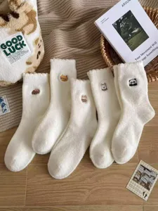 Detail shot of cute embroidered fluffy winter socks in soft white wool, cozy and warm style.