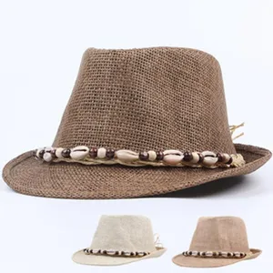Close-up detail of straw sun hat featuring decorative shell and wooden bead braided hat band.