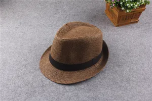 Detail shot of brown straw fedora hat, classic black band design, summer beach sun protection.
