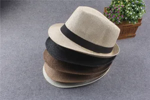 Detail view of stacked multi-color straw fedora hats with black bands, summer sun protection.