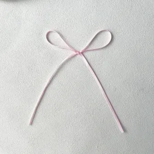 Close-up detail of a delicate pink ribbon bow, thin 0.3cm decorative bow for cake and crafts.