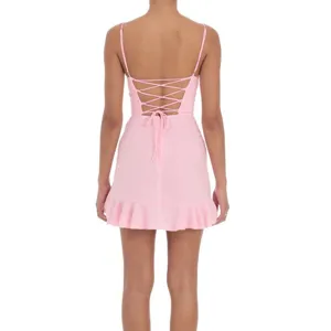 Back detail view of pink lace-up minidress with delicate straps and ruffled hemline.