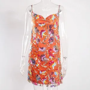 Detail shot of a women's sexy orange sequin floral slip dress with chain straps for party.