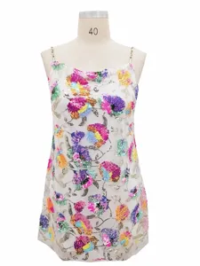 Detailed view of colorful sequin floral embroidery and gold chain strap on white mesh dress.