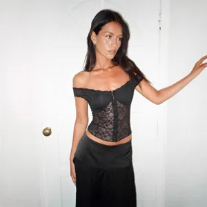 Vista dettagliata del top corsetto in pizzo nero con spalle scoperte e delicato motivo floreale