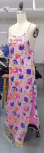 Detailed view of pink sequin floral long dress with gold chain straps and side slit design.