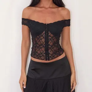 Dettaglio in primo piano del corsetto in pizzo nero con trama floreale trasparente.