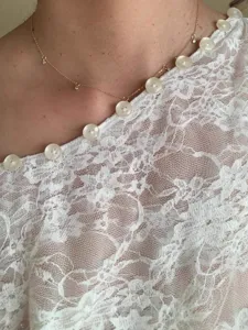 Detail view of sexy cutout lace button blouse and delicate necklace, elegant feminine fashion top.
