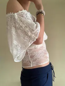 Detailed view of women's white off-shoulder lace top showing delicate sleeve button trim.