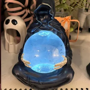 Detailansicht der blau leuchtenden Kristallkugel des Todesgottes in Skeletthänden.