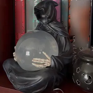 Detailansicht einer Sensenmann-Statue, die eine große mattierte Kristallkugel hält.