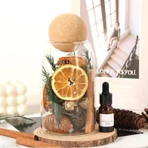 Dekoratives Glasgefäß mit getrockneten Orangenscheiben, Zapfen, Zimt und Duftöl-Diffusor.