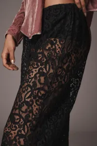 Vista dettagliata di pantaloni ampi in pizzo nero abbinati a una giacca in velluto rosa.