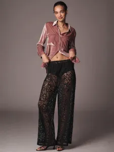 Sexy pantaloni larghi in pizzo nero abbinati a un'elegante camicia di velluto rosa.