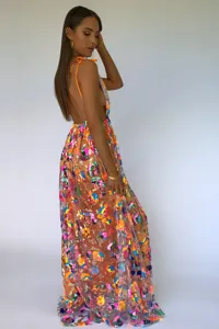 Close-up detail showing the colorful sequin and floral embroidery texture on the long dress.