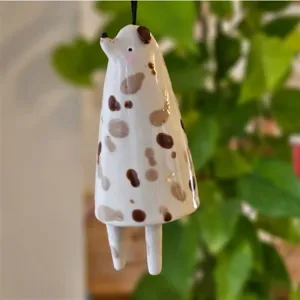 Detailaufnahme einer handgefertigten Keramikglocke in Hundeform mit braunen Flecken.