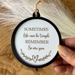 Detail eines Holzanhängers mit dem inspirierenden Spruch 'SOMETIMES life can be tough'.