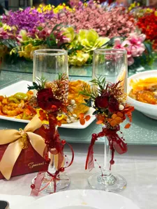 Bicchiere da champagne da matrimonio decorato con fiori secchi e nastri rossi per cerimonie.