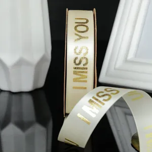 Primo piano dettagliato di nastro crema stampato in oro con testo per confezioni regalo.