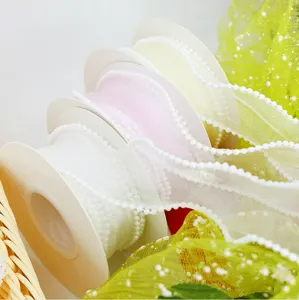 Dettaglio ravvicinato di nastro in organza con perle bordo onda rotolo per confezioni floreali.