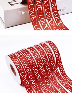 Red ribbon roll with white love text and heart patterns for Valentine gift wrapping and decor.