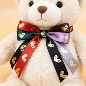 Primer plano detallado de un tierno oso de peluche con lazo colorido y corazones dorados.
