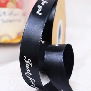 Primo piano dettagliato di nastro in poliestere nero con testo bianco per confezioni regalo.