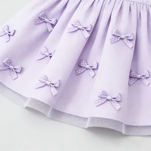 Dettaglio di tessuto gonna viola chiaro con fiocchi a pois bianchi e bordo in pizzo.