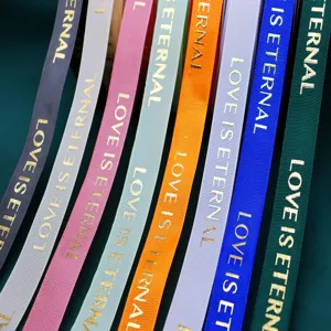 Close-up detail of colorful ribbons with gold foil stamped English text, smooth texture.