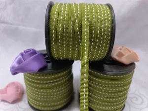 Dettaglio rotolo nastro verde con impunture per lavori artigianali e confezioni regalo.