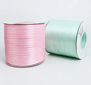 Detailed view of 0.3cm solid color polyester ribbon rolls in pink and mint green for crafts.