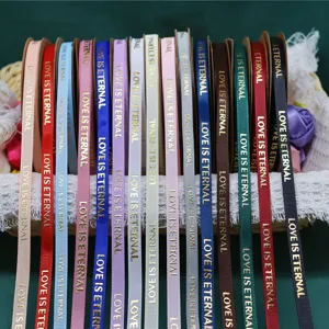Close-up of colorful grosgrain ribbons with gold foil love text for gift packaging.