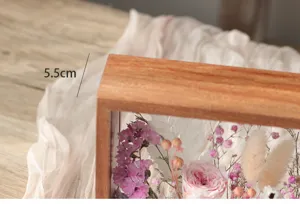 Vue détaillée d'un cadre vitrine en bois avec des fleurs séchées et préservées colorées.