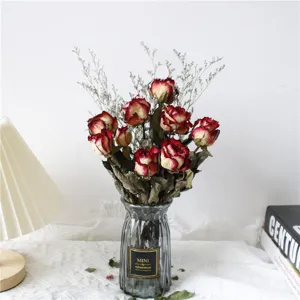 Natural dried red rose flower bouquet with baby's breath in glass vase for home decor.
