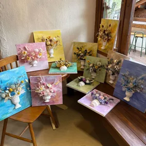 Detailed view of handmade 3D oil painting dried flower wall art with mini vases in a workshop.