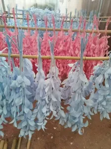 Detailed view of dried preserved leaf bundles hanging on bamboo poles in soft colors.