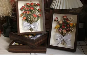 Vista detallada de rosas secas en marco de cuadro de madera con cinta decorativa.
