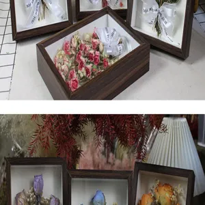 Marco de caja de sombra de madera con espécimen botánico de rosa seca y decoración de cinta.