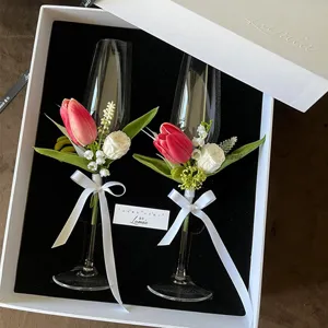 Calici da champagne per matrimonio decorati con fiori secchi stabilizzati in una confezione.