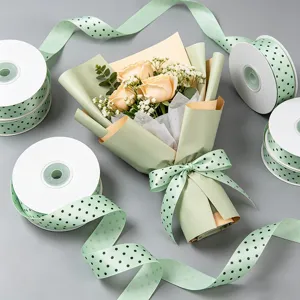Detailed view of light green polka dot ribbon rolls and bouquet wrapping for gifts and floral design.
