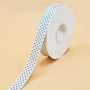 Vista dettagliata di un rotolo di nastro a pois bianchi da 2.5 cm per decorazione.