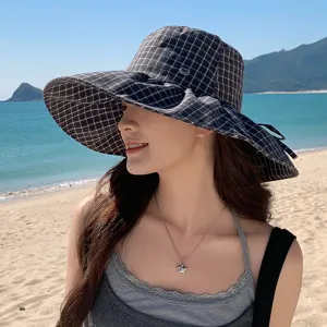 Vue détaillée d'un élégant chapeau de soleil à carreaux à large bord, idéal pour la plage.