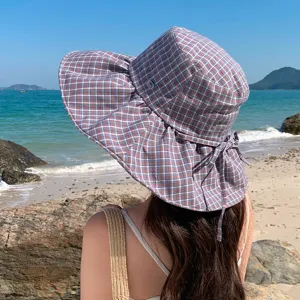 Vue détaillée d'un chapeau de soleil à carreaux élégant à large bord pour l'été sur la plage.