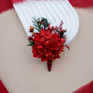 Close-up detail of red preserved flower boutonniere, wedding corsage with hydrangea and berries.