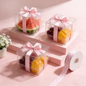 Transparante plastic fruitgeschenkdozen met roze bedrukte decoratieve linten voor feestjes.