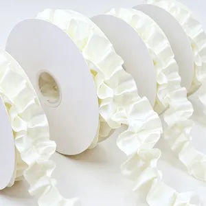 Close-up detail of elegant white pleated satin ribbon rolls for gift wrapping and hair bow crafts.