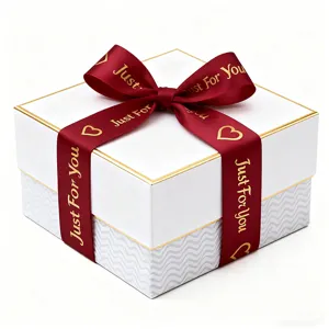 Dettaglio in primo piano di una confezione regalo bianca con bordo dorato e nastro.