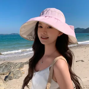 Detailaufnahme des Sonnenhutes am Strand mit rosa und beige Design sowie schöner Schleife.