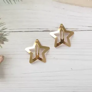 Metal star hair clip detail shot, showing the shiny gold pentagram shape and snap clip back.