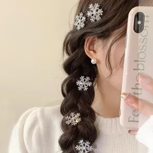 Close-up detail of rhinestone snowflake hair clips and pearl earrings on braided hair style.